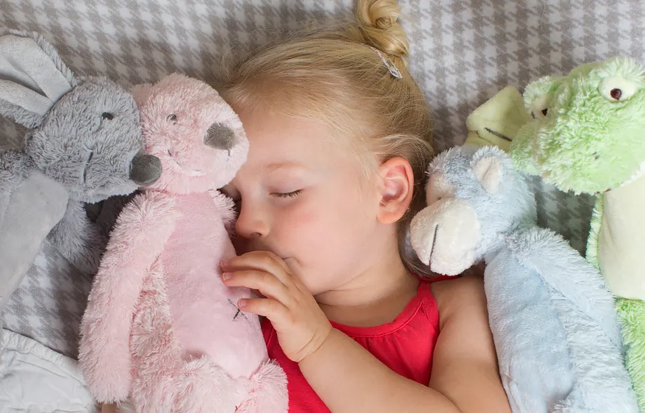 Enfant endormi entouré de peluches